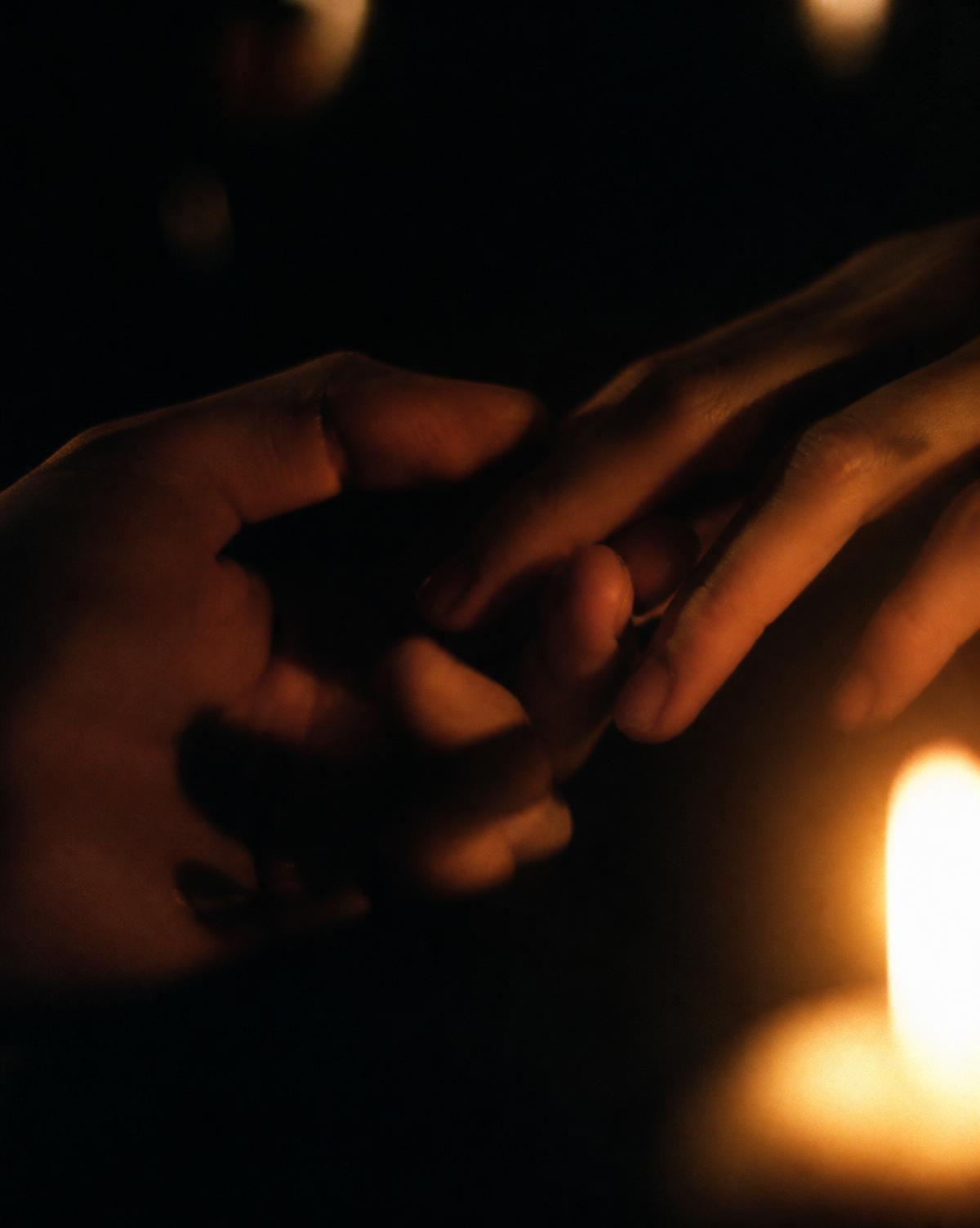 Dos manos que se encuentran a la luz de una vela
